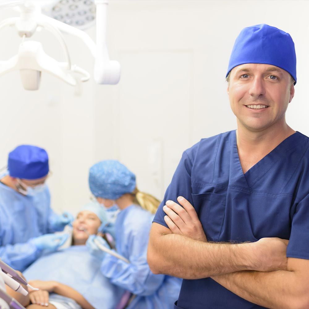 A dentist and patient undergoing treatment in the background